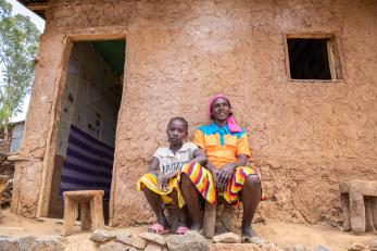 Manase and her daughter sitting outside their doorway