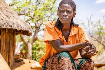 Ganasse seated outdoors looking into the distance with her hands folded in front of her