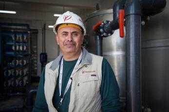 A man wearing a mercy corps vest and hard hat, smiling