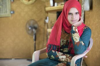 Lebanese woman stares at camera while seated in a room.