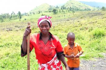 Sifa pictured with her young son, leaning on a farming tool