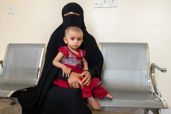 A woman with a young child dressed in red sitting on her lap in yemen