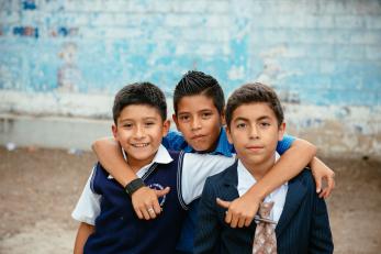 Three boys with arms around each other in guatemala