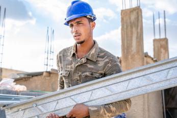 Young jordanian construction worker assembling structural building parts.
