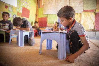 A boy attends class in a tent in an informal settlement outside mafraq, jordan