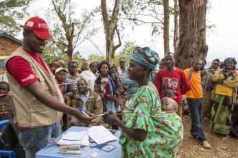 A mercy corps staff member hands a participant a name-tag. 