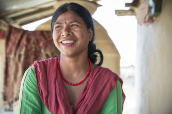 A young person in nepal smiles while looking away from the camera.