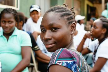 A young person in a group of people looks over their shoulder at the camera.