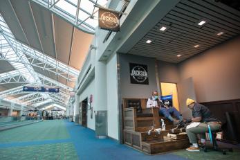 A person shines shoes at their shoeshine stand in a quiet airport impacted by the covid-19 pandemic.