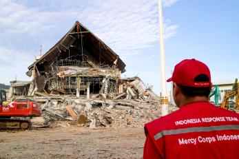 A person surveys damage to a building. 