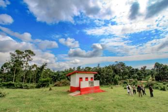 A group of people stand outside a recently constructed latrine. 