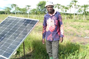 A farmer standing next to a solar panel. 
