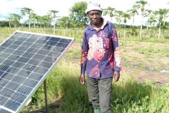 A farmer standing next to a solar panel.