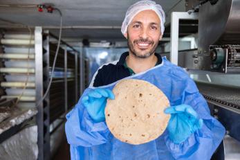 A baker holding freshly baked bread.