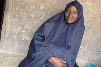 Woman sitting against a wall outside