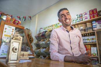 Jordanian man behind shop counter, smiling.