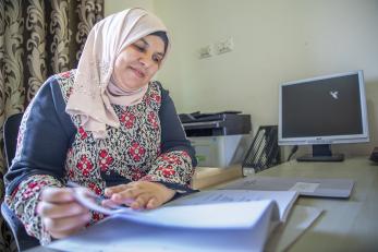 Jordanian woman sitting in office space reviewing documentation.