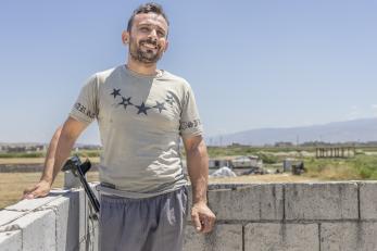 Syrian man stands on rooftop overlooking his farm.