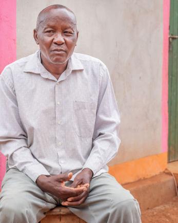 A man sits with his hands folded in his lap in kenya