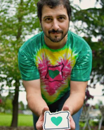 Man outside holding small map of portland with heart in the middle