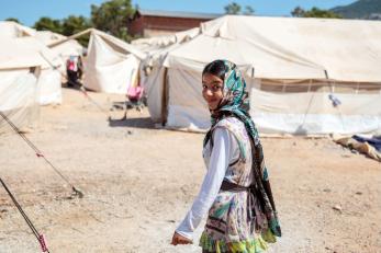 Girl in green scarf smiling at refugee camp