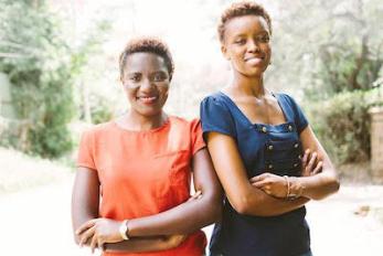 Two women standing shoulder to shoulder with arms crossed, smiling