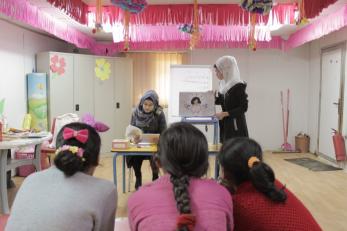 A group of three girls listening to two young women present