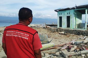 Arianto, Senior Program Officer, surveys a plea for help spray painted in Malay ("TOLONG"), on the ruins of a building in the devastated coastal village, Loli Tondo. Photo: Genadi Aryawan for Mercy Corps