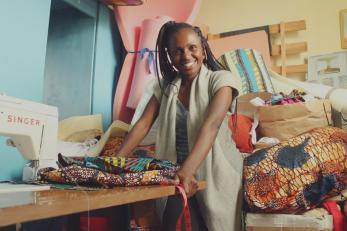 Smiling woman next to a table with a singer sewing machine and textiles