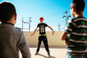 Sepan performing with two other boys looking on