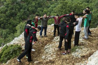 Group of young men standing outdoors in a circle with arms around each other's shoulders