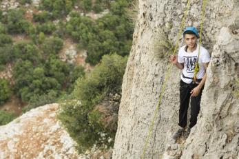 Mohammad Khaldoun takes a short rest before completing the climb. Mercy Corps staff take Syrian refugee youth rock climbing, among other wilderness therapy activities. All photos Isidro Serrano Selva for Mercy Corps.