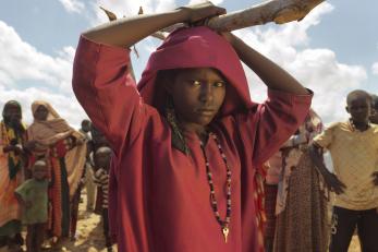 Girl holding a large stick over her head with people in the background