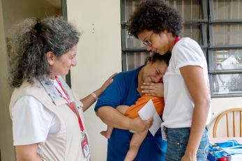 Mercy Corps team members Karla Peña, right, and Pardis Barjesteh, comfort a crying Stephanie, 27, after she received cash and a water filtration system from them. PHOTO: Angel Valentin for Mercy Corps