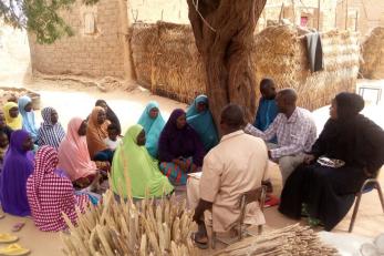 A group of community members gathered outdoors, seated