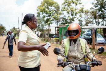 Lucy talking to a man who is on a motorcycle