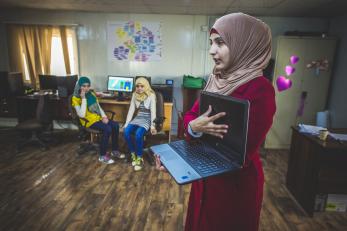A woman showing a laptop computer to a group