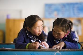 Two girls writing at a desk in Mongolia