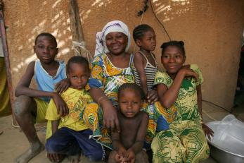 Woman with five children sitting outside house