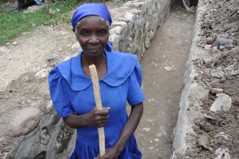 Haitian woman pictured cleaning and renovating a drainage ditch.