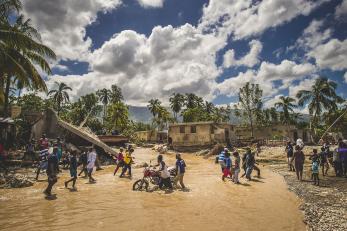 Haitians crossing flooding river in their community