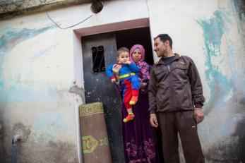 Syrian refugee family in front of structure.