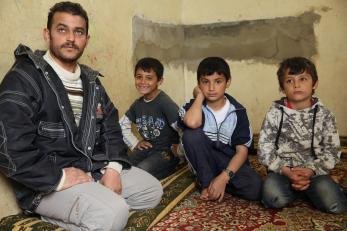 Abid, who fled to Lebanon from Syria one year ago, sits with four of his eight children in the cowshed they're now forced to call home.