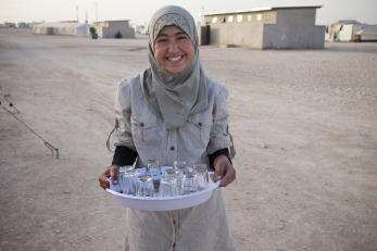 Nour holding a platter of glass teacups