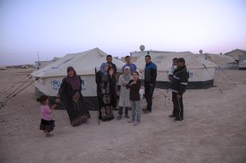 A family gathers outside their tents in a refugee camp