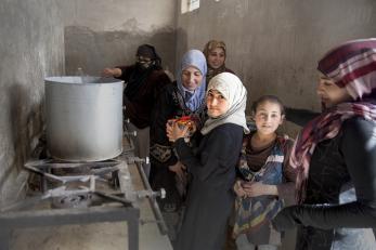 Women and girls cooking with a large pot