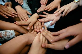 Several hands reaching to the center