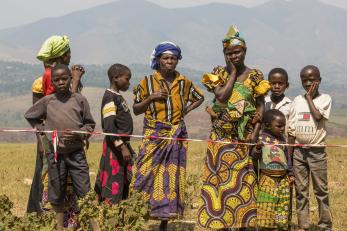 Woman and children standing behind a strip of red and white tape in DRC