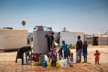 Families get water from a tank at a refugee camp