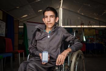 A young man in a wheelchair holds a smartphone